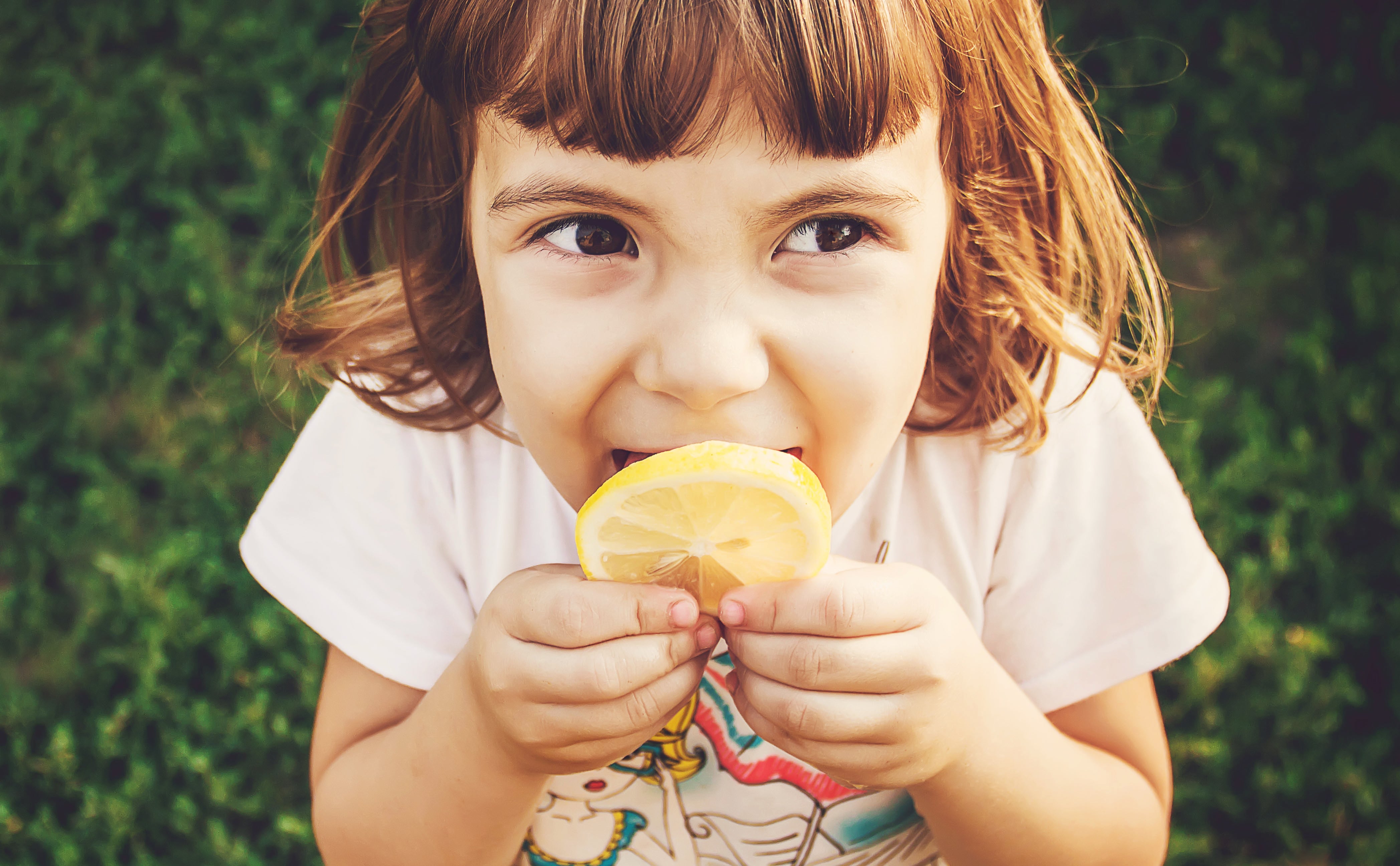 Young girl eating a lemon