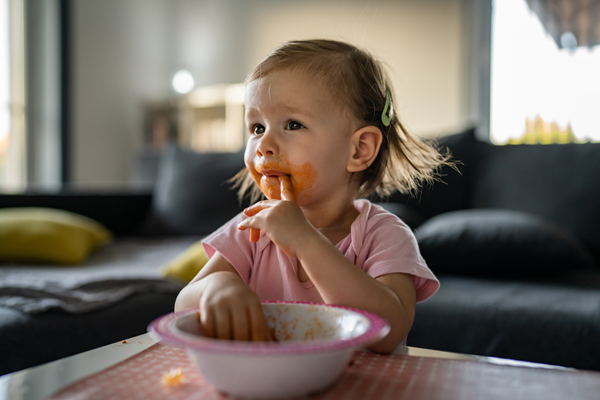 Baby eating out of a bowl with her fingers