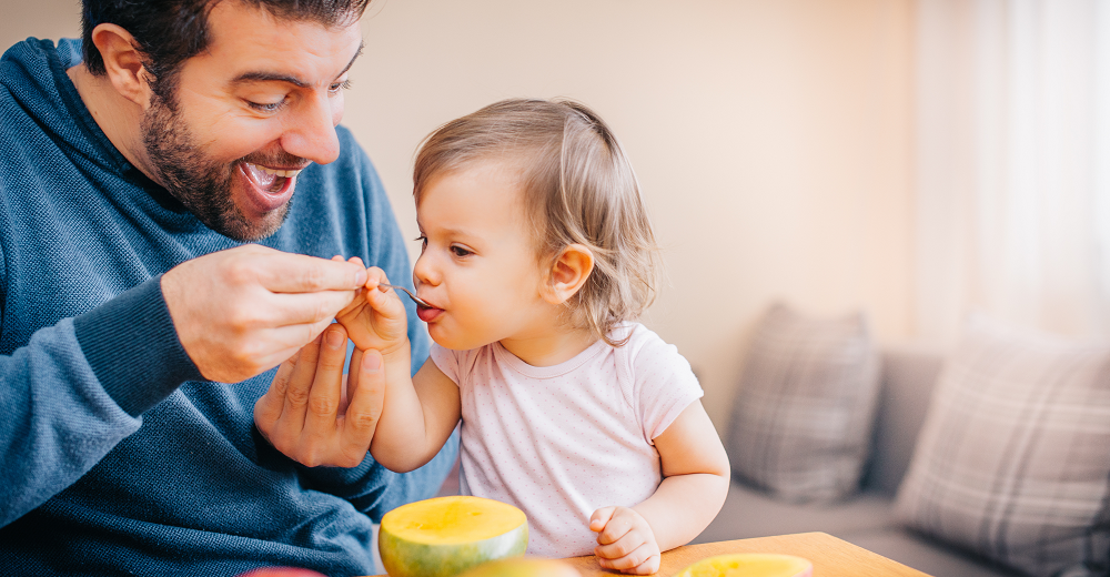 Father spoon feeding infant baby.