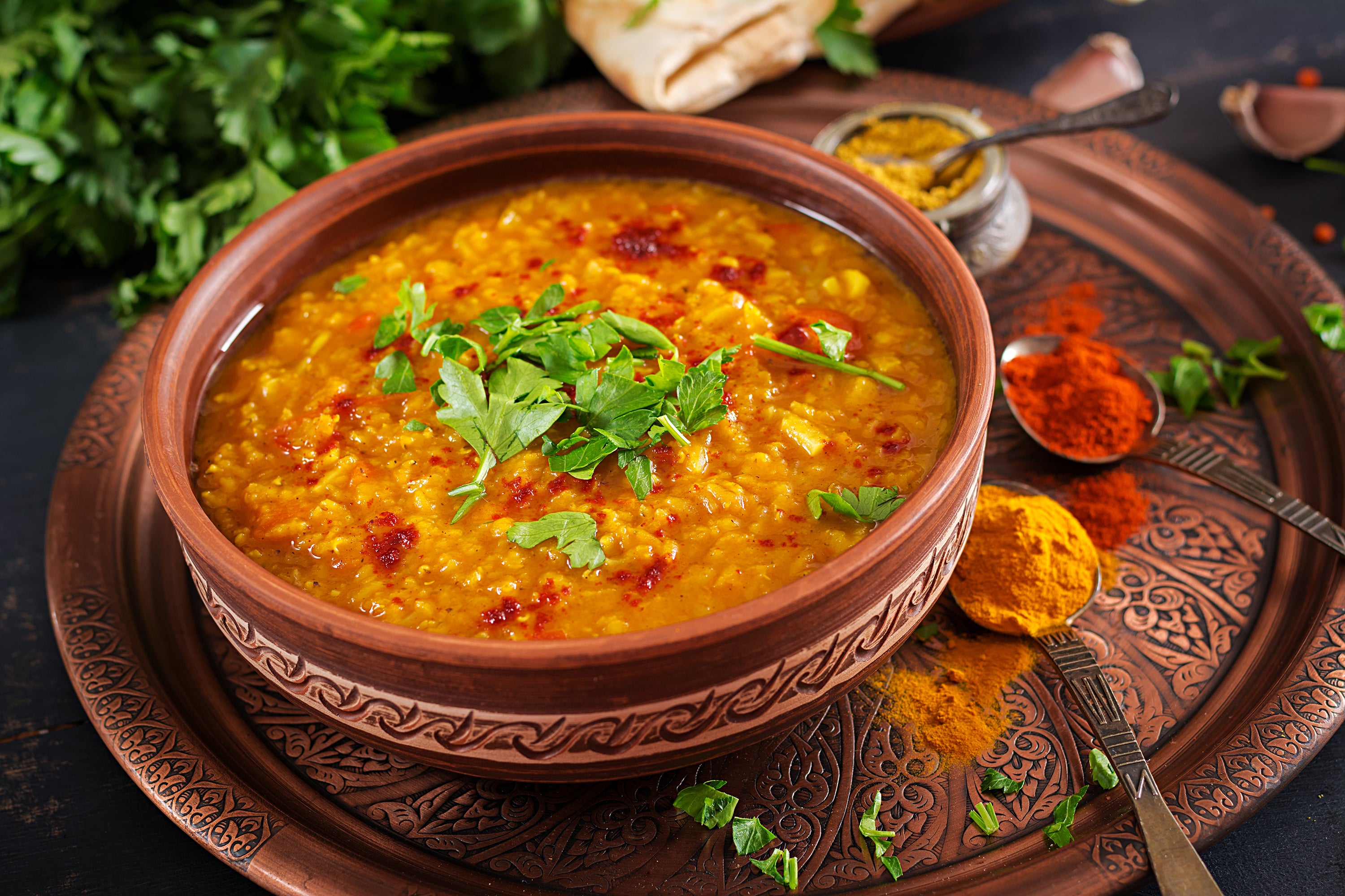 Indian Spiced Lentils is made with lentils, spices such as mustard powder, cumin, and coriander, and vegetables such as onions and tomatoes.