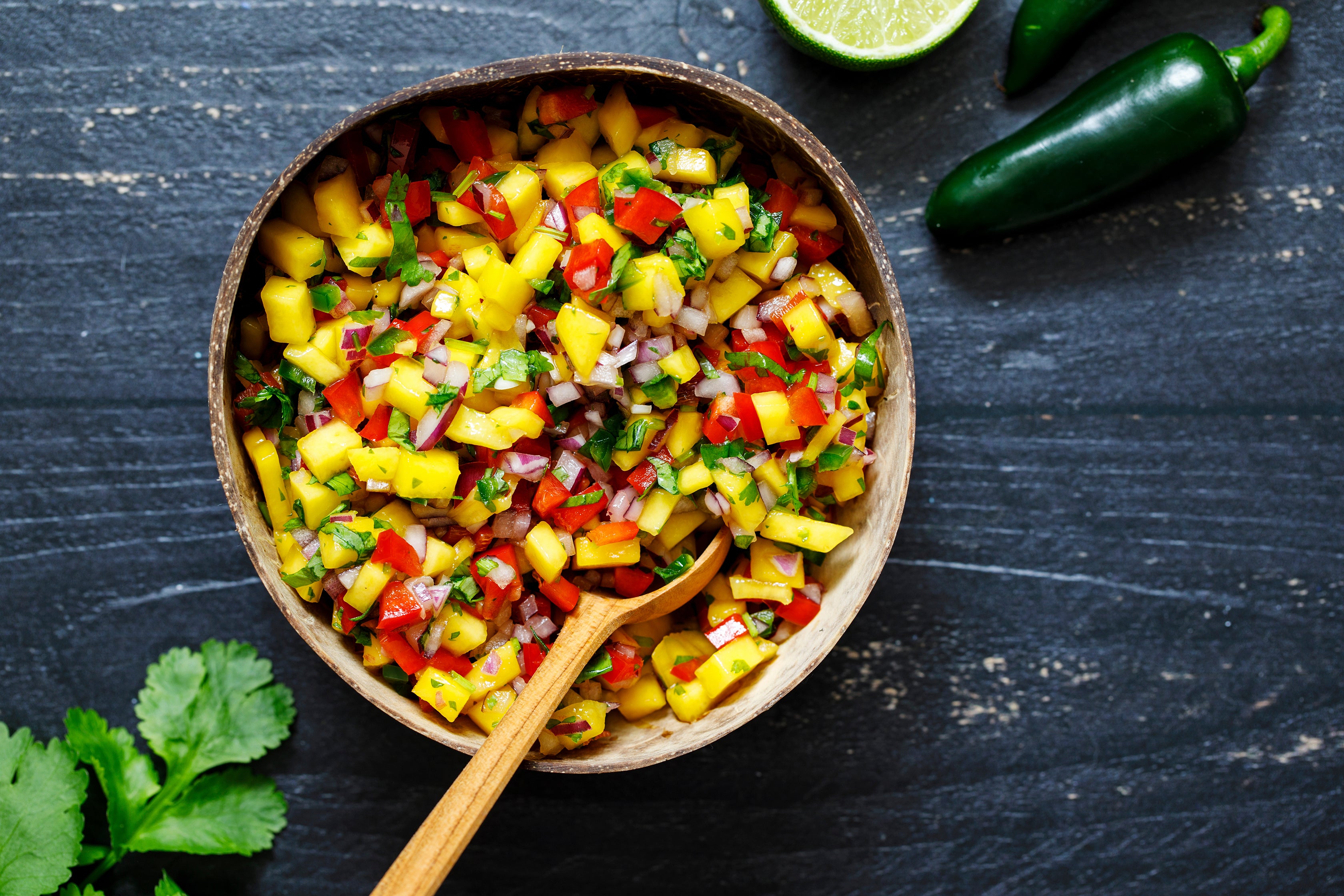 Fresh ingredients in mango salsa, including diced mango, red onion, jalapeno, and lime juice.